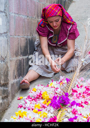 A Salvadoran woman decorates palm fronds with flowers during the Flower & Palm Festival in Panchimalco, El Salvador Stock Photo