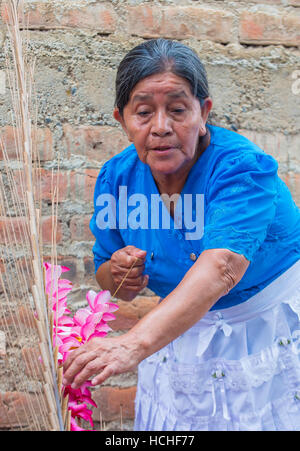 A Salvadoran woman decorates palm fronds with flowers during the Flower & Palm Festival in Panchimalco, El Salvador Stock Photo