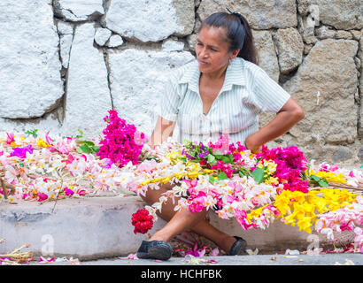 A Salvadoran woman decorates palm fronds with flowers during the Flower ...