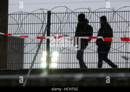 Hamburg, Germany. 9th Dec, 2016. People walk behind a barbed wire fence erected by the police at Sternschanze station in Hamburg, Germany, 9 December 2016. About 50 ministers of foreign affairs participate in the conference of the Organization for Security and Co-Operation in Europe between 8 and 9 December in Hamburg. Photo: Bodo Marks/dpa/Alamy Live News Stock Photo