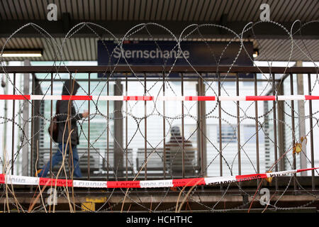 Hamburg, Germany. 9th Dec, 2016. People walk behind a barbed wire fence erected by the police at Sternschanze station in Hamburg, Germany, 9 December 2016. About 50 ministers of foreign affairs participate in the conference of the Organization for Security and Co-Operation in Europe between 8 and 9 December in Hamburg. Photo: Bodo Marks/dpa/Alamy Live News Stock Photo