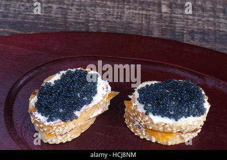 Sandwiches with black caviar on a wooden tray. Stock Photo