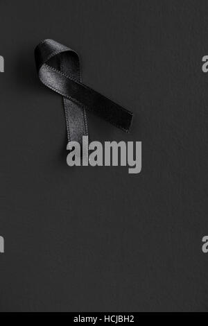 Black satin ribbon on black background. R.I.P. symbol. Stock Photo