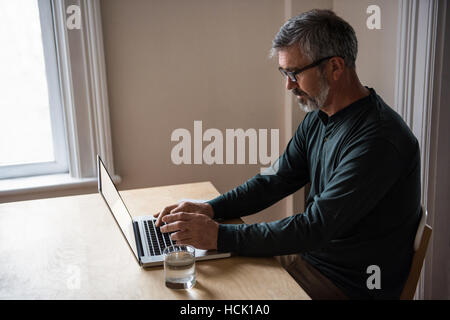 Man sitting at table and using laptop Stock Photo