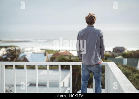 Rear view of man standing on balcony Stock Photo