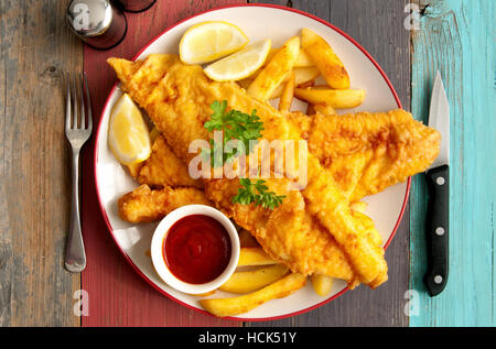 Close up of two pieces of battered fish on a plate with chips Stock Photo