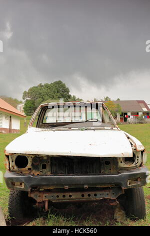 Rear view of the rusty-wormy-rotten remains of an old abandoned pickup truck in the grounds of the local school and church of Olal village at the N. Stock Photo