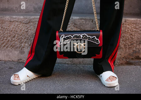 Woman with Love me tender Pinko black and red bag before Prada fashion show, Milan Fashion Week street style on September 22 Stock Photo