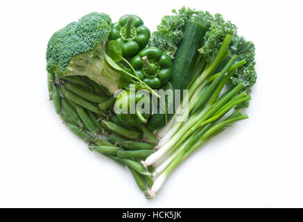 Selection of green vegetables and leaves including kale and broccoli in the shape of a heart over a white background Stock Photo