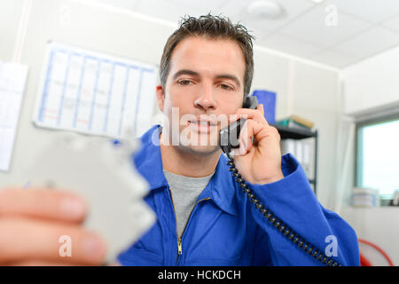 Man on telephone, holding unfocused electrical component Stock Photo