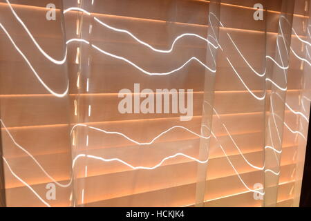 Slightly open shutters in a room reflecting on the curtain Stock Photo