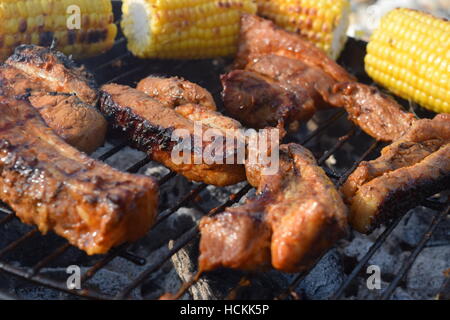 Crispy pork ribs on a charcoal barbecue with sweetcorn at the Isle of Wight in England Stock Photo