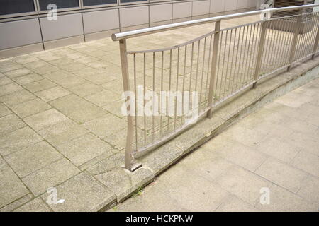 Damaged silver railing on the curb of the road Stock Photo