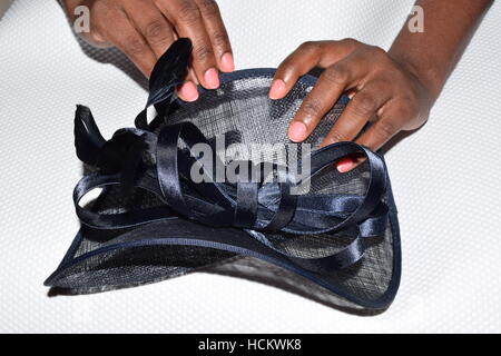 Womans' hands holding a  fancy hat on a white surface Stock Photo