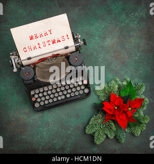 Vintage typewriter with Christmas decoration and red poinsettia flowers. Merry Christmas! Vintage style toned picture Stock Photo