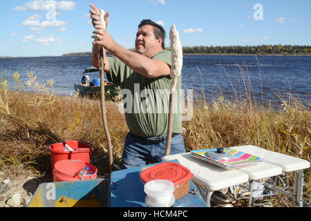 An indigenous man making bannock on a stick, a native North American food similar to bread, in Northern Ontario, Canada. Stock Photo