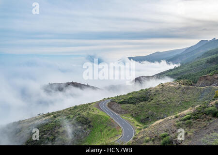 road in mountain landscape over clouds - cloudy panorama Stock Photo