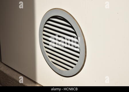 Round air vent on a white wall close to the floor Stock Photo