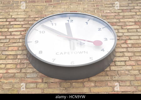 Large clock showing time from Cape Town on a brick wall; view from underneath Stock Photo