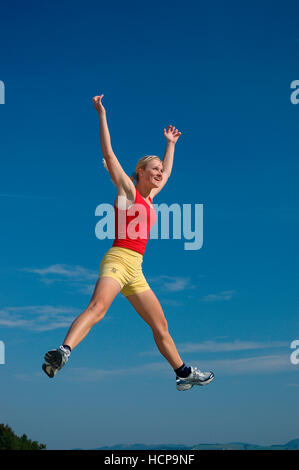 Young blonde woman jumping, joyful Stock Photo