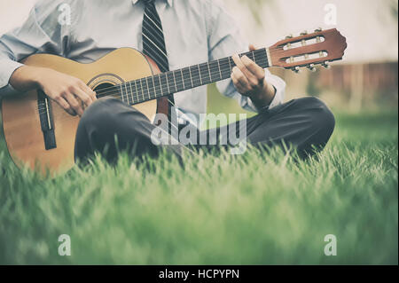 Young man playing the guitar in the grass