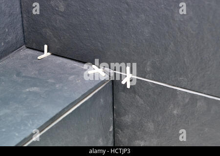 Installing the tiles with plastic crosses on the wall. Stock Photo
