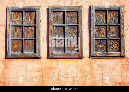 Old rustic three wooden window on orange wall background. Stock Photo