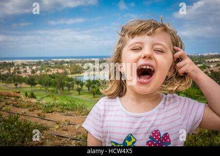 Little girl standing on a viewpoint over Maspalomas in gran Canaria and shouting loudly Stock Photo