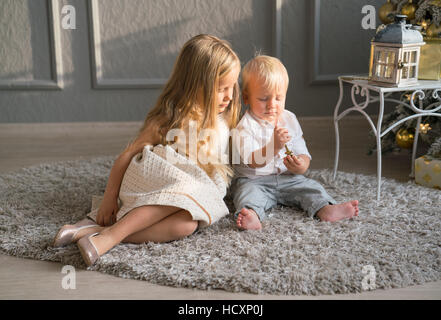 Cute children playing together near Christmas tree indoors. Stock Photo