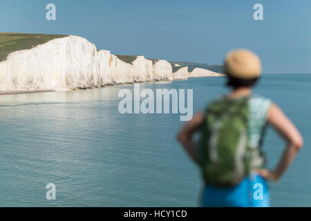 A woman looks towards the Seven Sisters while walking the South Downs Way, South Downs National Park, East Sussex, UK Stock Photo