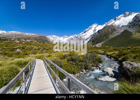 A hiking trail crosses wooden bridge over a creak high up in the mountains, South Island, New Zealand Stock Photo