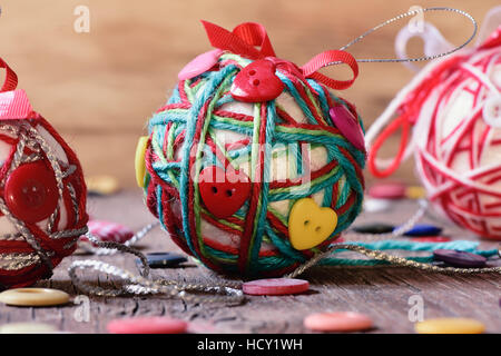 closeup of some handmade christmas balls, made with ribbon bow, strings and buttons of different colors, on a rustic wooden surface Stock Photo