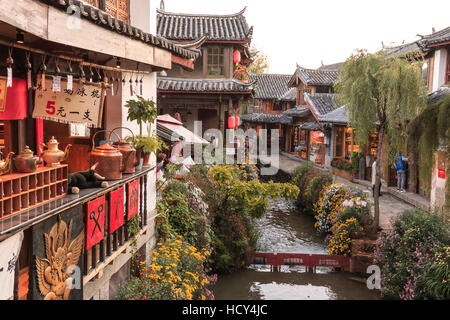 Lijiang, China - November 10, 2016: Panoramic view of one of the canals in Lijiang Old Town at sunset with some tourists passing by Stock Photo