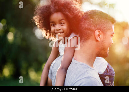 Father carrying daughter on back outdoors Stock Photo