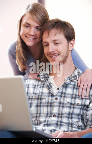 Young Couple Looking At Laptop Together Stock Photo
