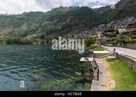 San Antonio Palopó, Guatemala, sits on the steep hillsides along Lake Atitlan. Five boys play in a cayuco on a small dock in the foreground. Stock Photo