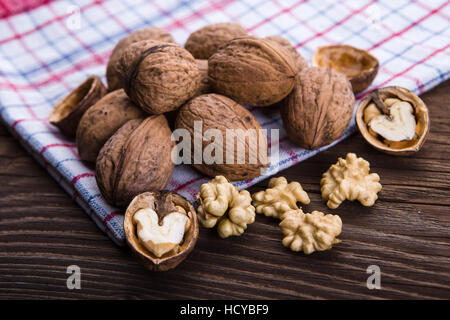 Walnut kernels and whole walnuts on old wooden table and dish towel Stock Photo