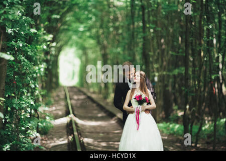 Happy wedding couple charming groom and perfect bride posing in park Stock Photo