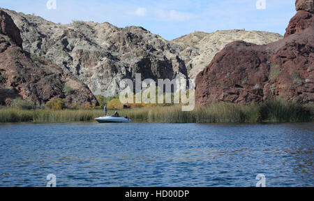 Pleasure boat on Lake Havasu with the beach grasses and red mountains and white mountains Colorado River Stock Photo