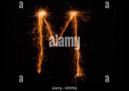 Letter M made of sparklers on black Stock Photo