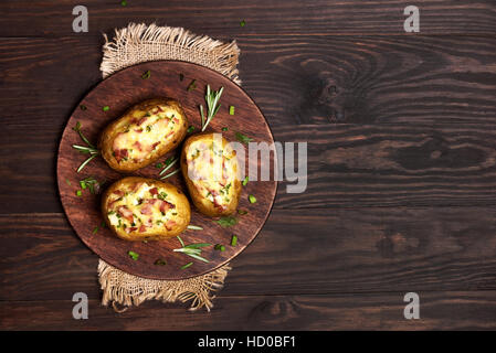 Baked stuffed potato with bacon, cheese and green onion on wooden background with copy space Stock Photo