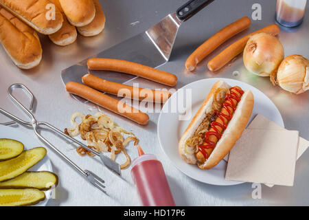 Preparing hot dogs in the stainless steel kitchen of a food truck or hot dog stand. Stock Photo