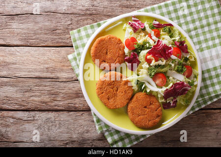 Dietary carrot cutlets and salad of chicory, cabbage and tomatoes close-up on a plate.  horizontal view from above Stock Photo