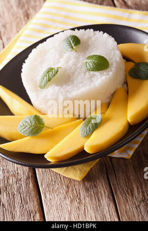 Thai dessert, Mango with sticky rice close-up on a plate on the table. Vertical Stock Photo