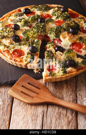 Delicious tart with chicken, broccoli, tomatoes and olives close-up on the table. vertical Stock Photo