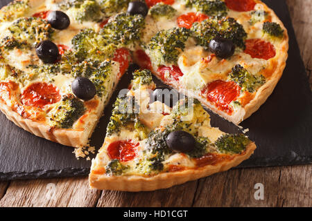 Sliced Quiche with chicken, broccoli, tomatoes and olives close-up on the table. horizontal Stock Photo