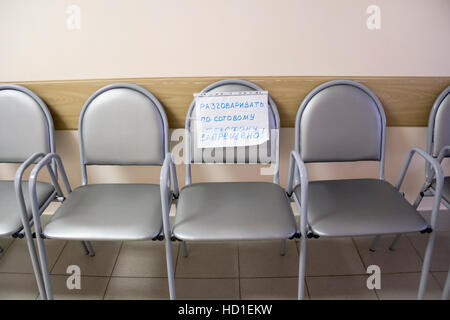 Row of chairs with an attached note in empty corridor Stock Photo