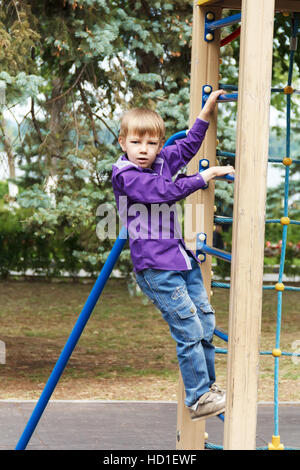 Cute boy climbing a rope ladder on the playground Stock Photo