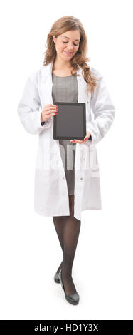 Young woman in white lab coat holding tablet computer with screen facing the camera full length, isolated on a white background Stock Photo