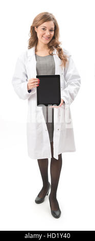 Young woman in white lab coat holding tablet computer with screen facing the camera full length, isolated on a white background Stock Photo